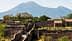 Ancient ruins of Pompeii with Mount Vesuvius visible in the background under clear skies. - Olive Oil Times