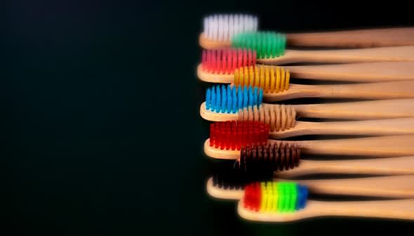 A row of bamboo toothbrushes with various colored bristles arranged in a line. - Olive Oil Times