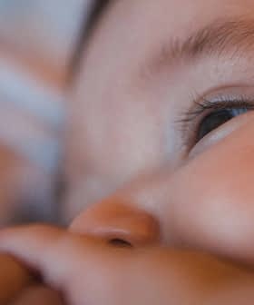 Close-up view of a baby's face with a focus on the eye and hand. - Olive Oil Times