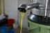 Stream of fresh olive oil flowing from a metal spout during the extraction process. - Olive Oil Times