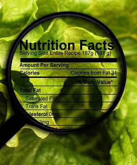 Magnifying glass focusing on nutrition facts label on leafy greens background. - Olive Oil Times