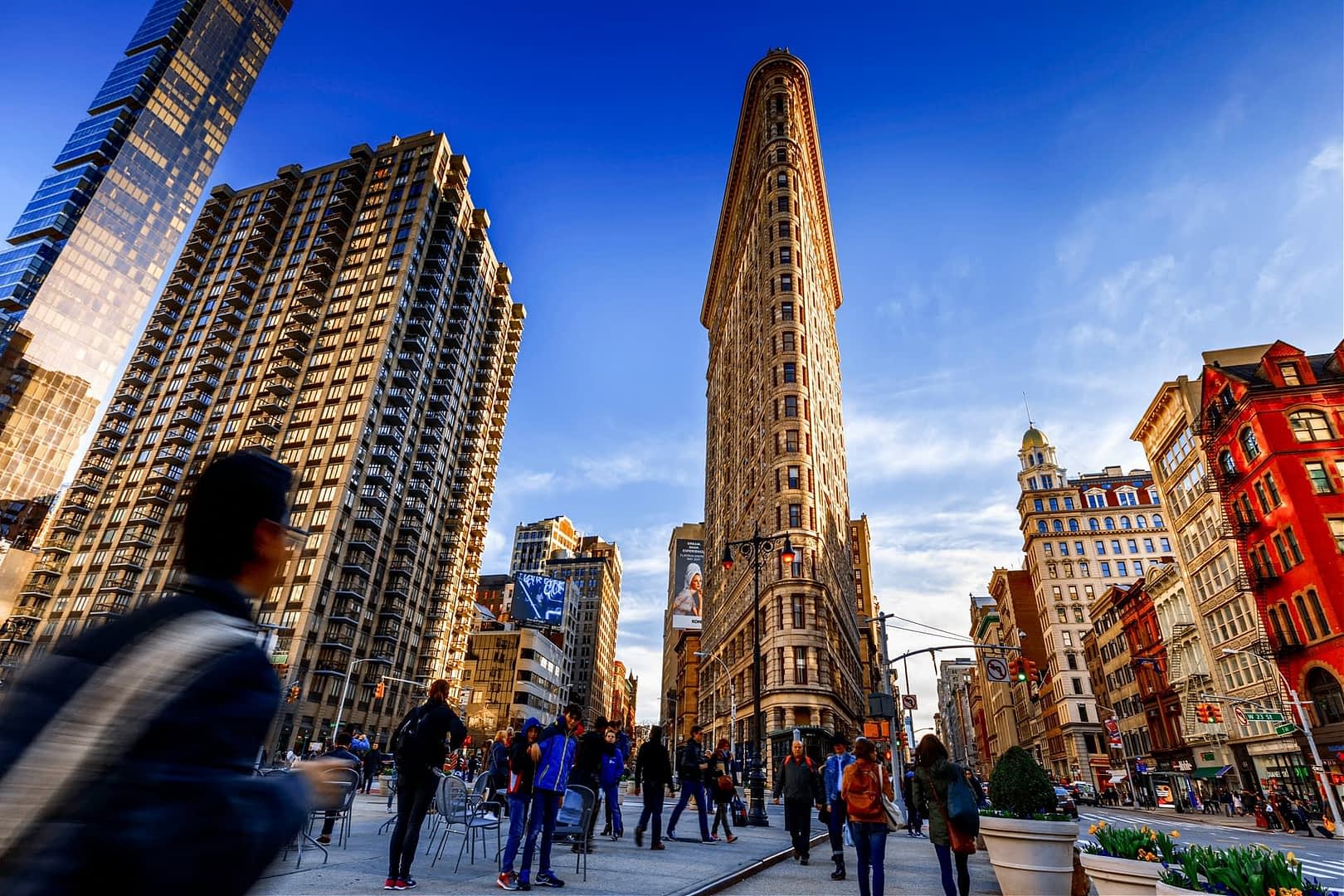 The Flatiron Building in New York City, a historic triangular skyscraper surrounded by other buildings. - Olive Oil Times