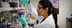 Female scientist in a lab coat and gloves handling samples in a laboratory setting. - Olive Oil Times