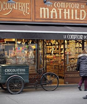Shopfront of Le Comptoir de Mathilde featuring a chocolatier display and a bicycle cart. - Olive Oil Times