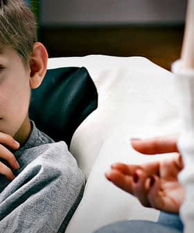 A young boy sitting on a bean bag, listening attentively to an adult speaking. - Olive Oil Times