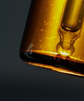 Close-up of an amber glass dropper bottle with a pipette top against a dark background. - Olive Oil Times