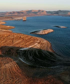 Aerial view of a reservoir with dry land and hills in the background during sunset. - Olive Oil Times