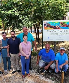 A group of nine individuals posing in front of a sign that reads 'The Garden of Peace'. - Olive Oil Times