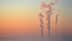Three smoke stacks emitting vapor into the sky during sunrise with a gradient of colors. - Olive Oil Times