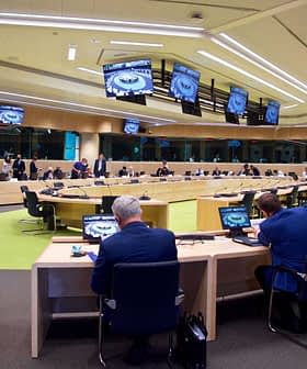 A large conference room with multiple tables and participants engaged in a meeting. - Olive Oil Times