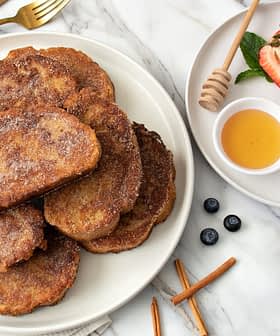 A plate of fried cinnamon French toast served with honey, berries, and a sprig of mint. - Olive Oil Times