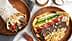 A pita wrap filled with beef, vegetables, and fries next to a plate of gyro with toppings. - Olive Oil Times