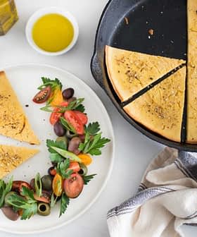 Sliced chickpea flour flatbread served with a fresh salad of tomatoes and greens. - Olive Oil Times