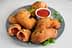 A plate of fried dough pieces garnished with green herbs and served with a small bowl of tomato sauce. - Olive Oil Times