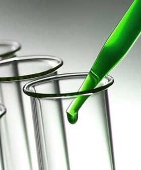 Green liquid being dropped into a glass test tube with a pipette. - Olive Oil Times
