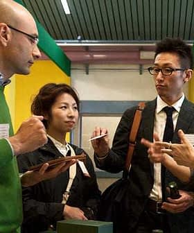 A group of four professionals discussing with tablets and pens in a modern setting. - Olive Oil Times