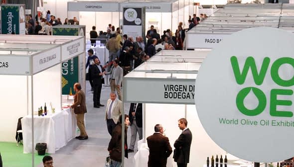 Exhibition hall with booths labeled for the World Olive Oil Exhibition and attendees interacting. - Olive Oil Times