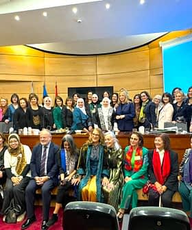 A group of women and men posing for a photo at a conference event in a formal setting. - Olive Oil Times